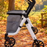 Zijkant nieuwe versie rollator voor binnen en buiten met tas in herfstomgeving